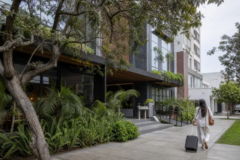 Contemporary hotel exterior in Lima with street trees and a pedestrian.