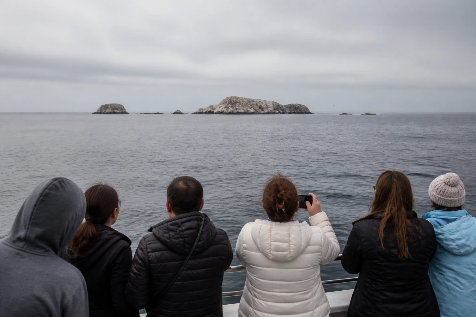 Passenger boat traveling on open water toward rocky islets off Callao